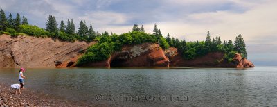 Panorama of children playing on pebble beach at sea caves of St Martins New Brunswick