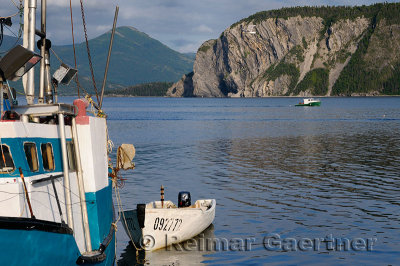 Fishing boat leaving East Arm Bonne Bay at Norris Point at the end of the day with Shag Cliff