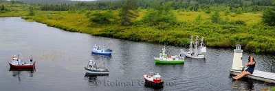 Panorama of model ships and lighthouse with girl on dock of river between Mobile and Witless Bay Newfoundland