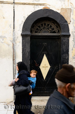 Mother and child and old man walking past a door in the old Medina Casablanca
