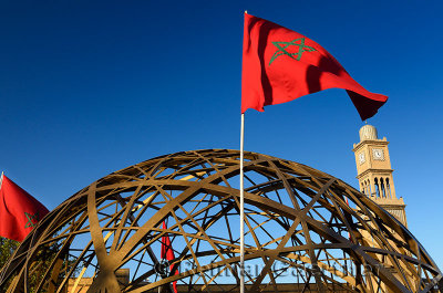 Casablanca sculpture and Moroccan flags with the clock tower of the Old Medina