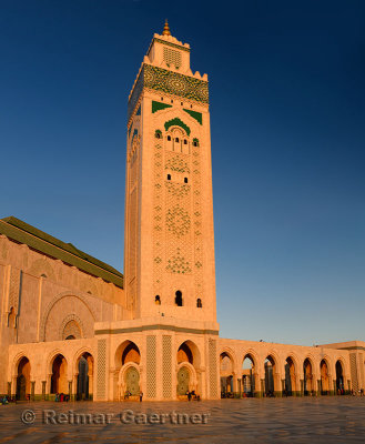 Golden Hassan II Mosque and minaret with blue sky at sunset