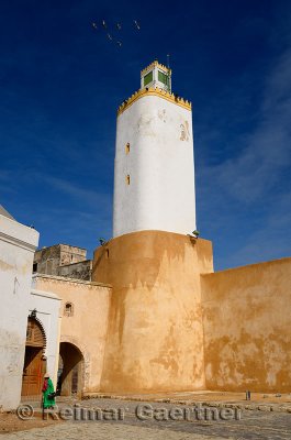 Grand Mosque minaret with old lady in green in Old Portuguese city of El Jadida Morocco