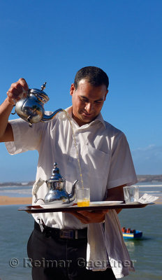 Server pouring mint tea for lunch at seaside resort at Oualidia Morocco