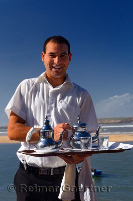 Friendly server offering mint tea for lunch at seaside resort at Oualidia Morocco