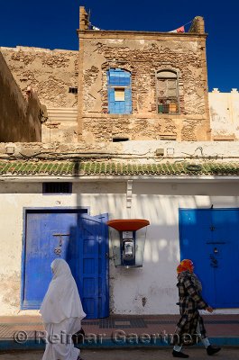 Modern telephone in an ancient Essaouira Medina street with two Morrocan women
