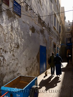 Mother and daughter walking down a narrow Essaouira Medina street in morning light