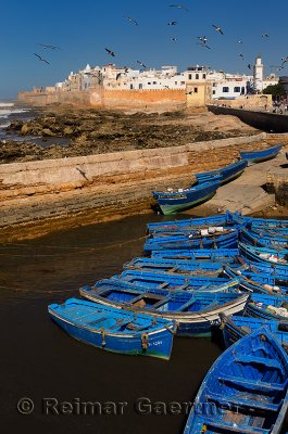 Blue fishing boats and the sea bastion ramparts of Essaouira Morocco