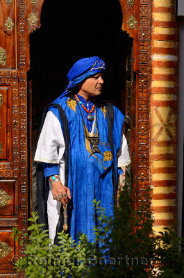 Profile of a traditional blue Berber Taureg man standing in wood carved doorway Marrakech Morocco