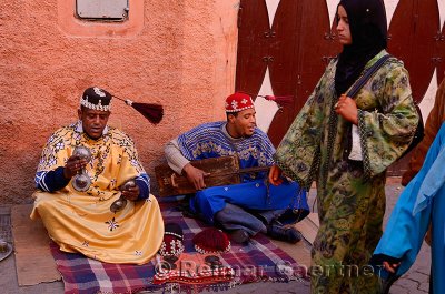 Happy Gnawa street musicians in Marrakech swinging their tarboosh tassels in time with women passersby