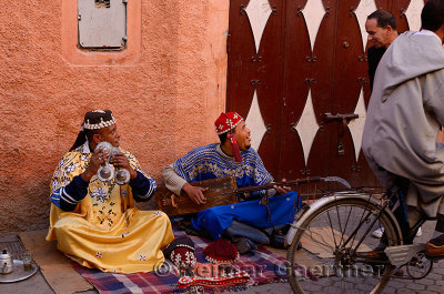 Gnawa street musicians playing hajhuj and krakeb in Marrakech talking to passerby