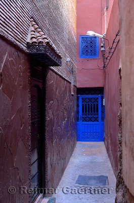 Narrow purple alleyway with cobalt blue door in Souk of Marrakech Morocco