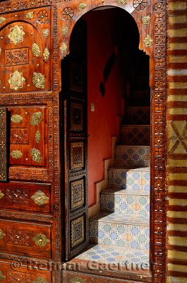 Ornate carved wood and brass door with tile steps in the Marrakech medina
