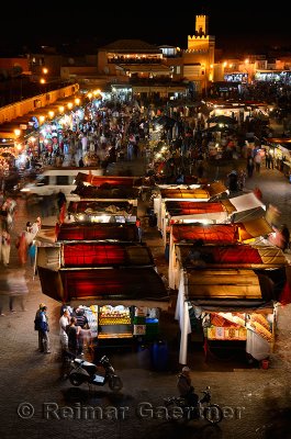 Overview of crowds at food booths and shops at night in Place Djemaa el Fna square Marrakech Morocco
