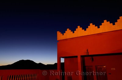 Orange adobe crenellations on rooftop of resort with indigo sunset in Tinerhir Morocco