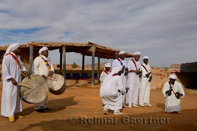 Group of Gnawa musicians in white robes dancing to krakeb and drum in Khemliya Morocco