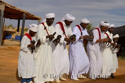 Group of Gnawa musicians in white turbans and jellabas dancing and playing krakebs in Khemliya Morocco