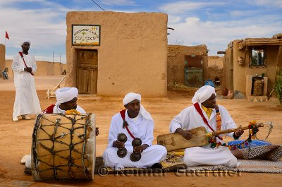 Gnawa music group in white turbans and jellabas sitting and playing music in Khemliya desert village Morocco