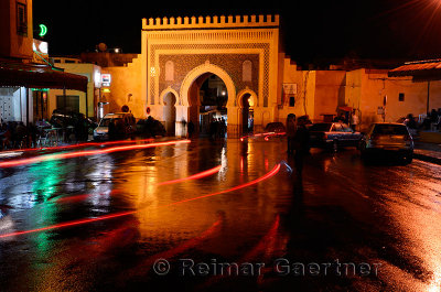 Car taillight reflections on wet Place Boujeloud with Blue Gate Morocco at night