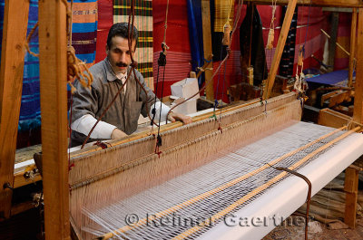 Weaver setting up a horizontal wooden hand loom in a cloth shop Fes Morocco