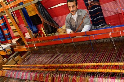 Weaver operating a horizontal wooden hand loom in a cloth shop Fes el Bali Morocco