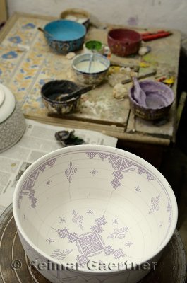 Hand painting glaze patterns on a bowl in a ceramic shop Fes el Bali Medina Morocco