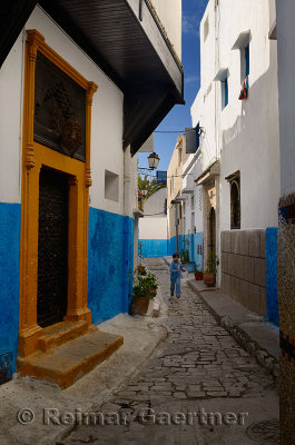 Young girl running along a narrow blue alley of Oudaia Kasbah Rabat Morocco