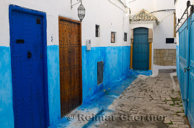 Brown door among blue doors in an alley of Oudaia Kasbah Rabat Morocco