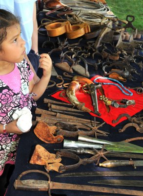 Young girl listening to presenter at table with old tools