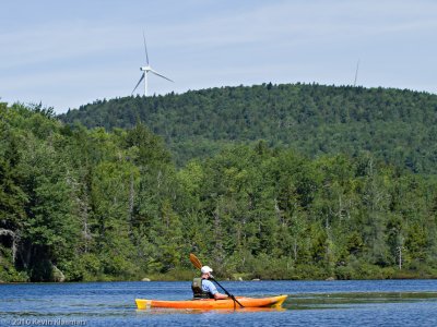 Bob paddles with a wind turbine towering overhead.