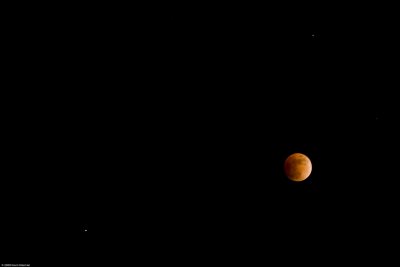 The moon near full eclipse flanked by Saturn and Regulus