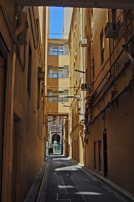 A glowing laneway without any streetart and just on large bin.