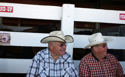 Two men sitting near the horse pens.