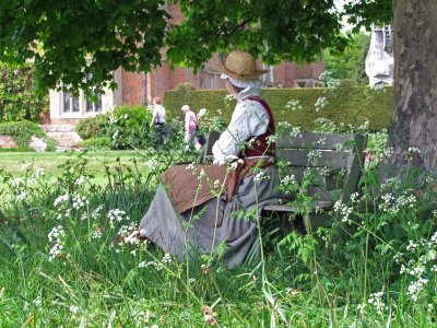 An Elizabethan maid relaxes in the shade of a tree.