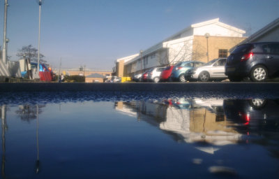 Hospital  wing  reflected  in  a  puddle.