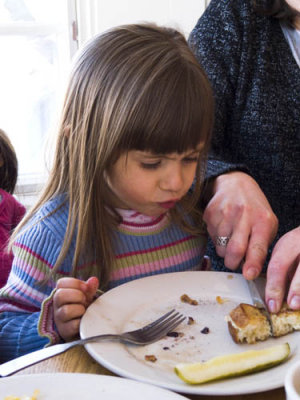 Mom helps to cut the sandwich.