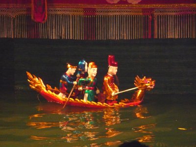 Puppets riding on a dragon boat.  A large rod supports the puppets under the water and is manipulated by the puppeteers.