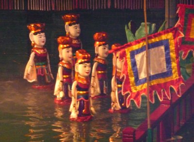 Some of the many puppets, which, in unison, appear to be moving over the water.