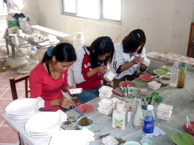 Young girls painting designs on ceramic ashtrays.