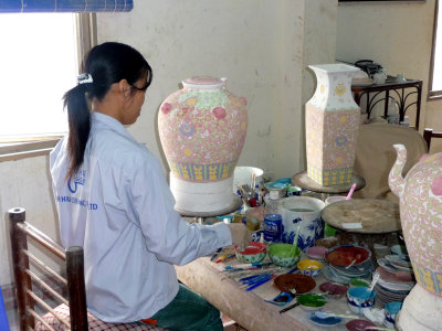 Vietnamese girl putting the glaze on these unfired ceramic pieces.