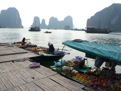 View of the floating market with rocky islets of Halong Bay in the background.