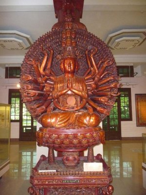 An intricate wooden carving of a Buddha with dozens of arms.