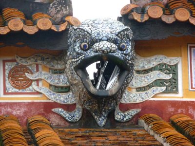 Close-up of a bird-like mosaic face on top of the gate.