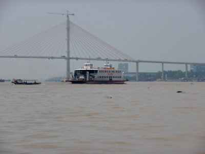 View of a ferryboat on the river with My Thuan Bridge in the background, the first cable-stayed bridge to cross it in Vietnam.