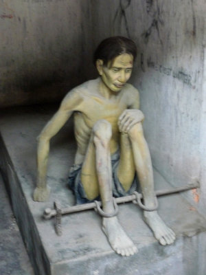 Mannequin depiction of a political prisoner shackled inside a Tiger Cage.
