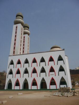Close-up of the modern mosque. Nearby, is a beach with many fishermen and fishing boats.