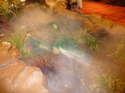 A replica of a crocodile in a rainforest environment.