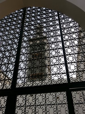 View of the minaret of the Grand Mosque through a decorative metal grating.