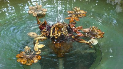 Elaborate metal sculpture in the fountain with a violinist and flower petals.