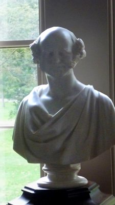A marble statue of Martin Van Buren in front of the window in the Library.